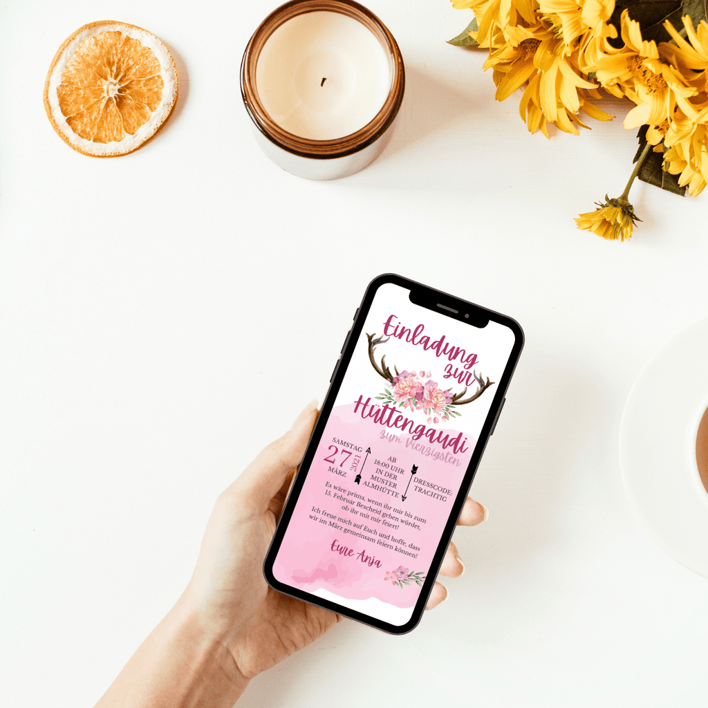 Einladung zur Hüttengaudi für Mädels: Auf einem Geweih sind rosa-lila Blüten in der Mitte aufgebunden, darum steht der Grund der EInladung. Alle wichtigen Infos sind auf dem rosa verwaschenen Hintergrund gut zu erkennen
