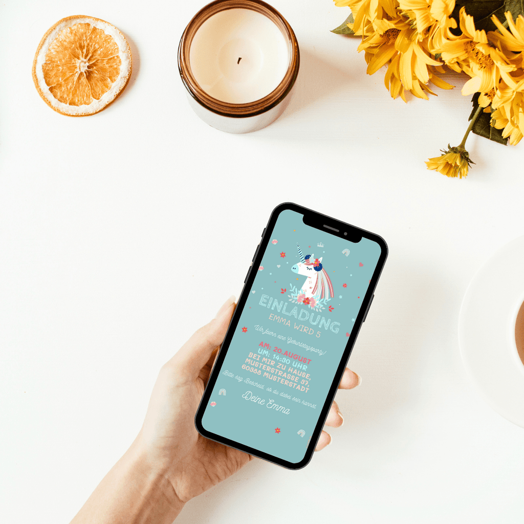 Einladungskarte für einen Kindergeburtstag mit einem wunderhübschen Einhorn auf hellpetrolfarbenem Hintergrund. Um das Einhorn und den persönlichen Einladungstext sind kleine Blümchen und zarte Regenbogen, Herzen und Kronen abgebildet.