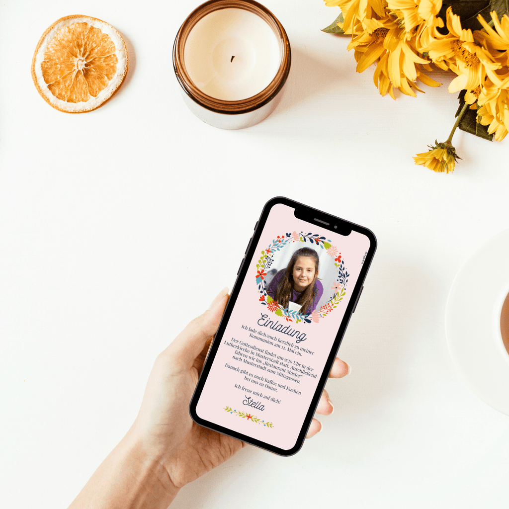 Eine Blumenkranz in den Farben grün, rot, hellblau, dunkelblau und rosa ziert das Bild  des Kommunionskindes, das seine Gäste mit dieser Einladung modern einlädt
