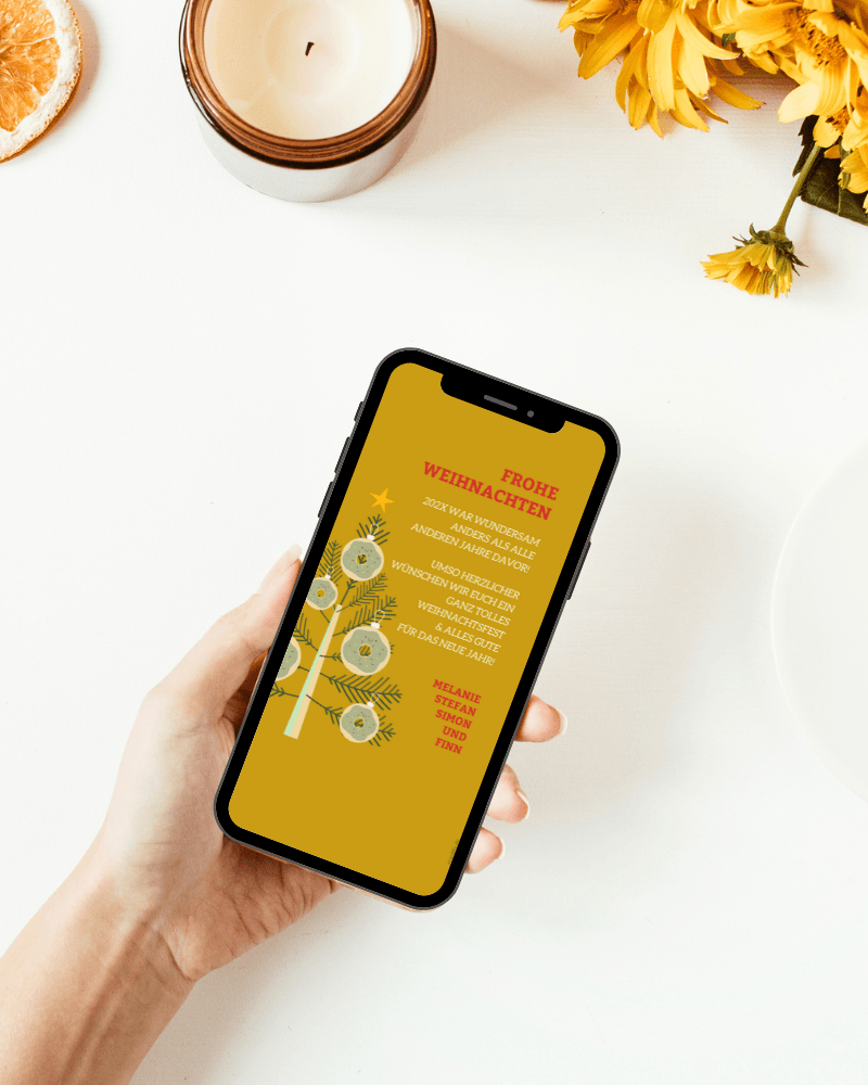 Digitale Weihnachtsgrüsse in senfgelb mit roter und weißer Schrift. Ein Tannenbaum mit Donut Weihnachtskugeln daran. de